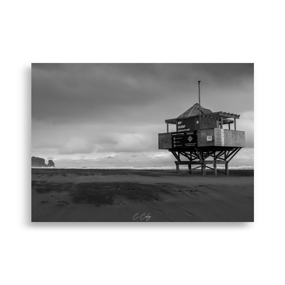 Photographie monochrome de l'emblématique abri sur pilotis des sauveteurs, dominant une plage néo-zélandaise, capturée par Charles Coley.
