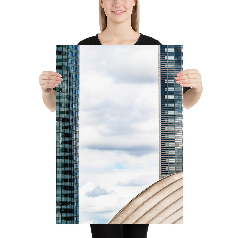 Fenêtre entre deux bâtiments en verre offrant une vue sur un ciel nuageux.