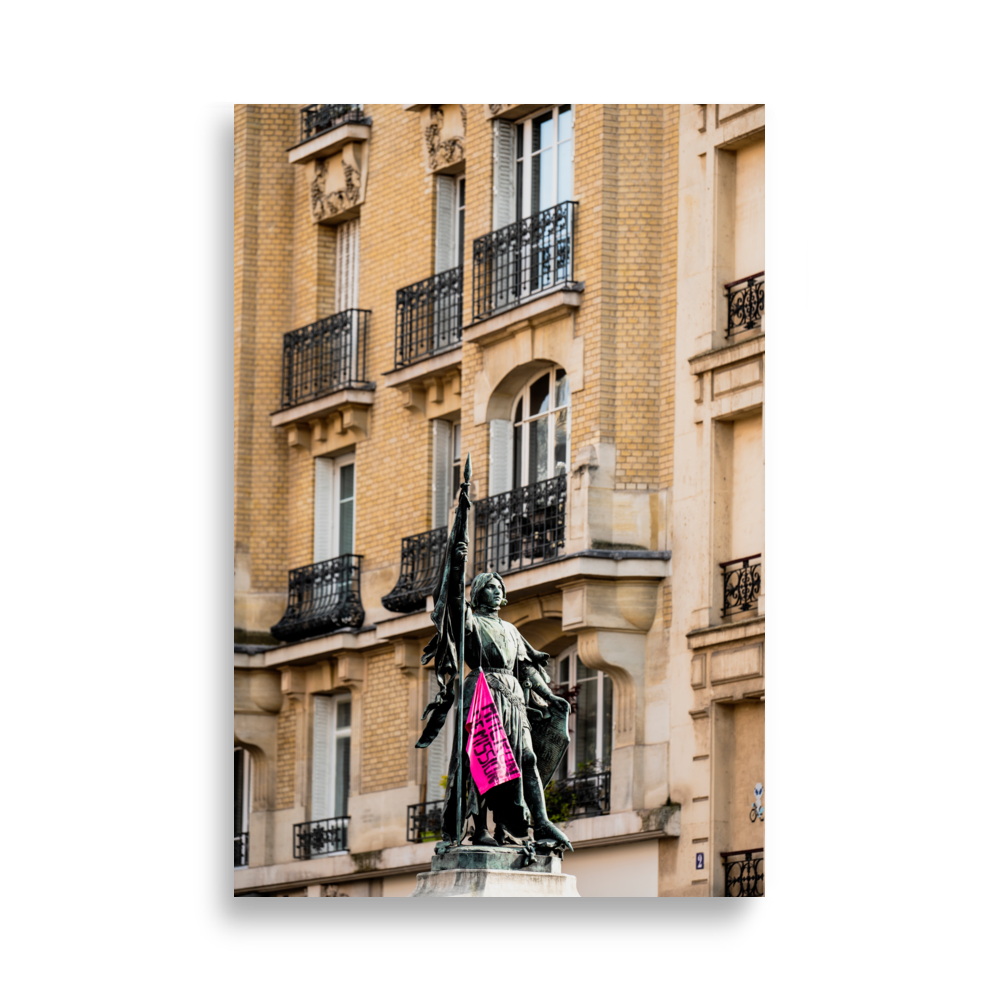 Poster de photographie d'une statue de Jeanne d'Arc ornée d'un drapeau rose de protestation.