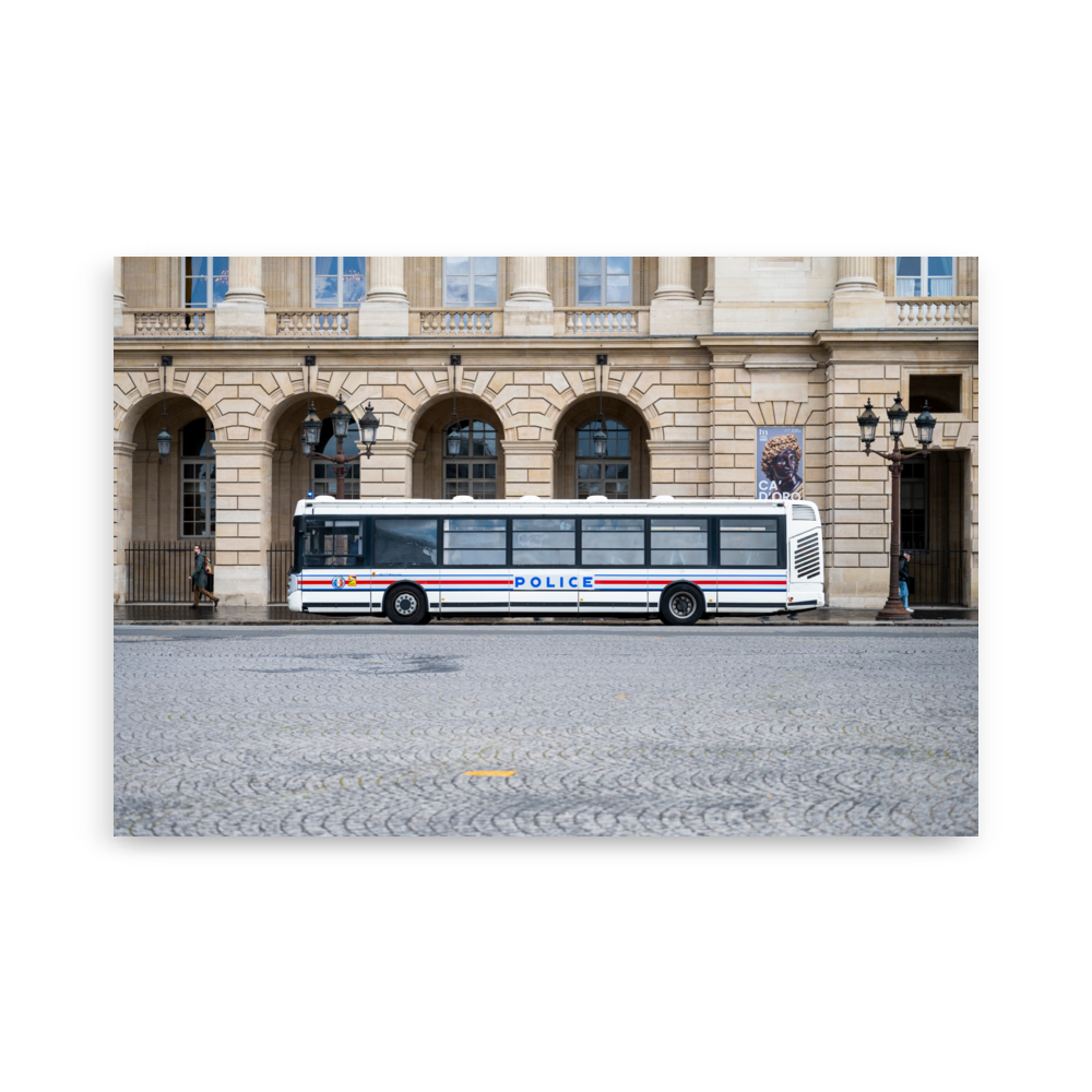 Photographie d'un bus de la police stationné sur une rue pavée à Paris, avec un bâtiment historique en arrière-plan.