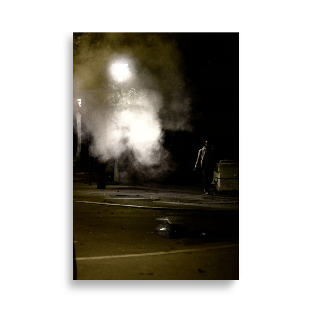 Photographie nocturne de Paris près du Rooftop Café Oz, montrant un homme passant à côté d'une fumée sortant d'une plaque sur le trottoir.