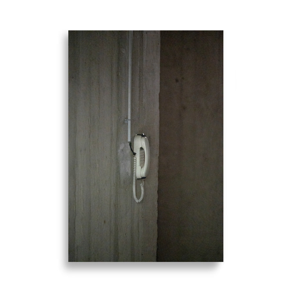 Téléphone vintage filaire contre un mur en béton, évoquant une époque révolue.