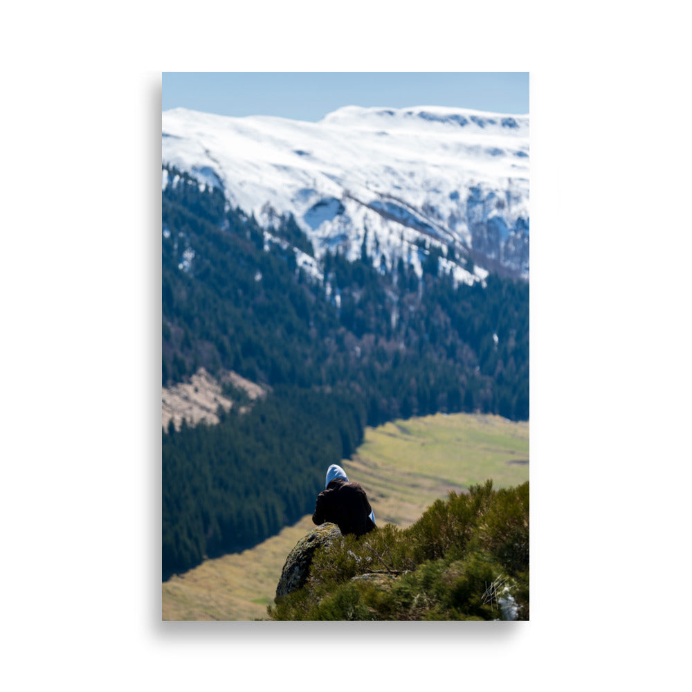 Figure en méditation sur une montagne du Cantal, vaste paysage en arrière-plan.