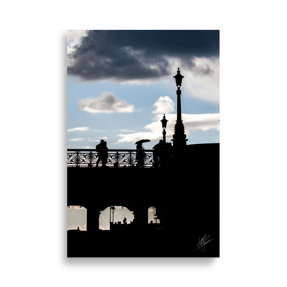 Des passants sur un pont parisien avec un ciel azur en arrière-plan, orné de nuages blancs et gris.