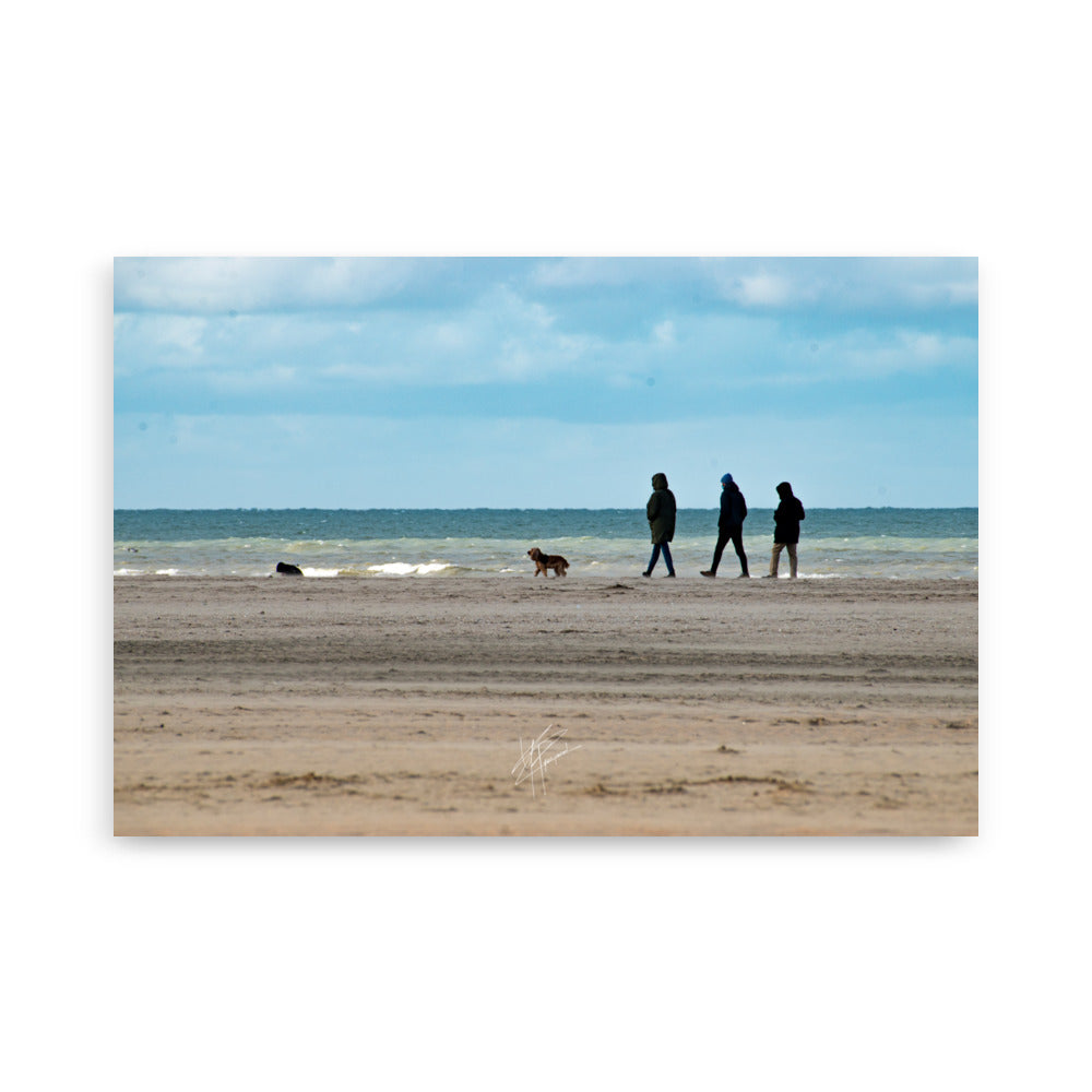 Photographie de la plage de Deauville avec des promeneurs et leur chien, capturant l'atmosphère tranquille et l'immensité de la mer normande.