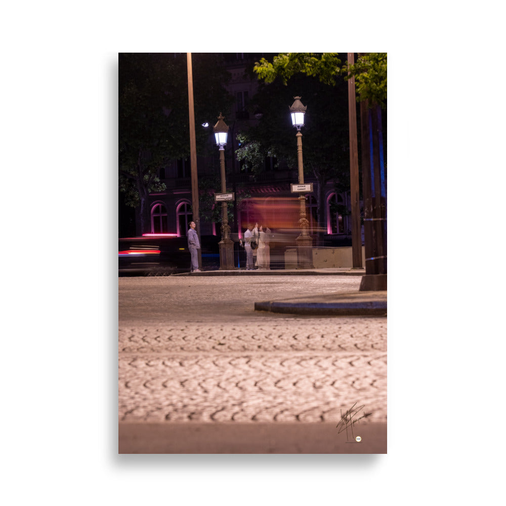 Photographie nocturne de l'Avenue de la Grande Armée à Paris, montrant quatre touristes prenant une photo, avec un arrière-plan de voitures en mouvement grâce à une longue exposition.