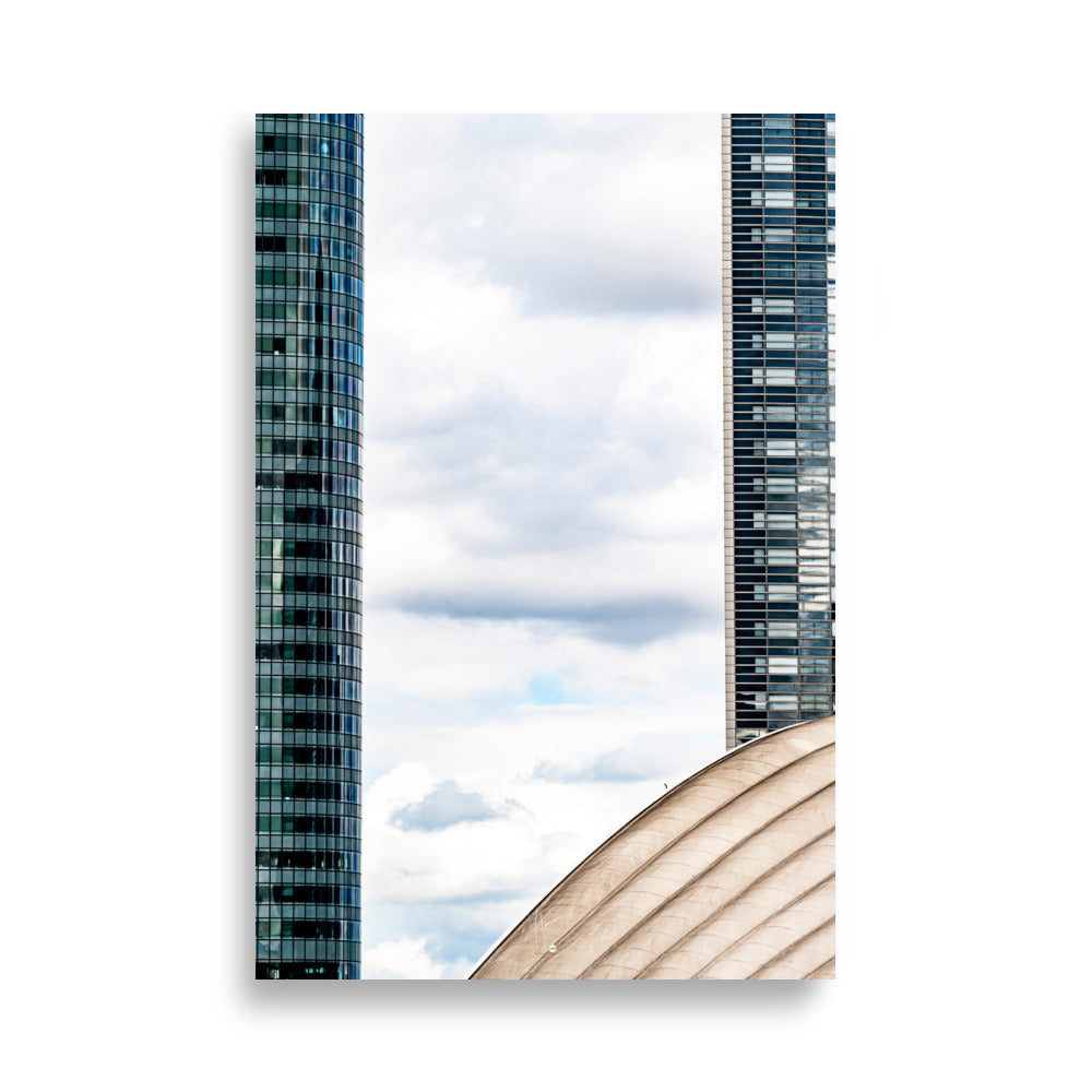 Fenêtre entre deux bâtiments en verre offrant une vue sur un ciel nuageux.