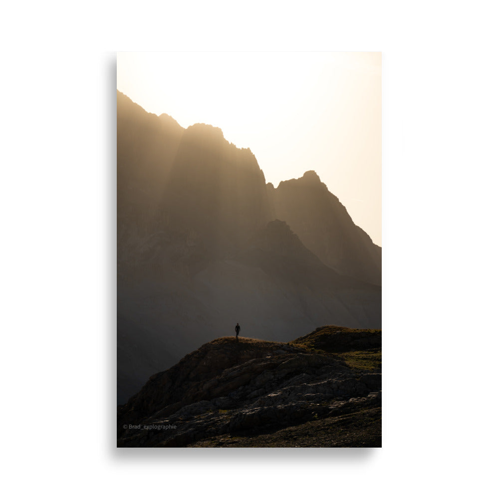 Vue panoramique des montagnes au coucher du soleil, où la lumière dorée enveloppe les pics et les vallées – une œuvre signée par Brad_explographie.
