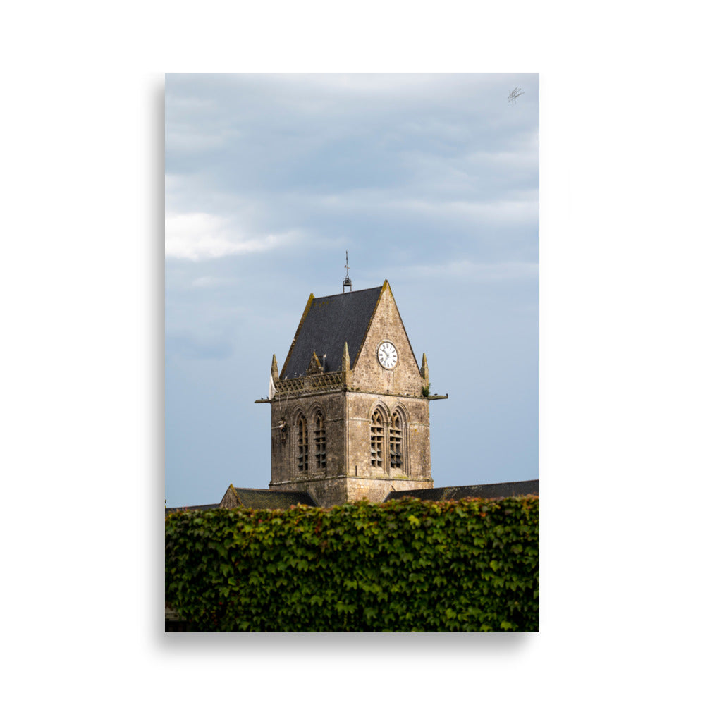 Vue pittoresque de l'église historique Sainte-Mère-Église sous un ciel nuageux, capturée dans un poster haut de gamme.