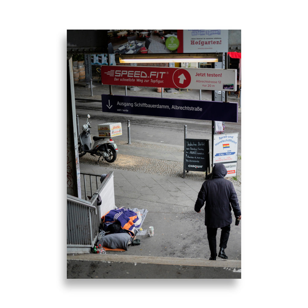 Photographie 'Contrastes de Berlin' montrant un homme sans domicile fixe reposant sous le métro berlinois, juxtaposé à un scooter de livraison alimentaire