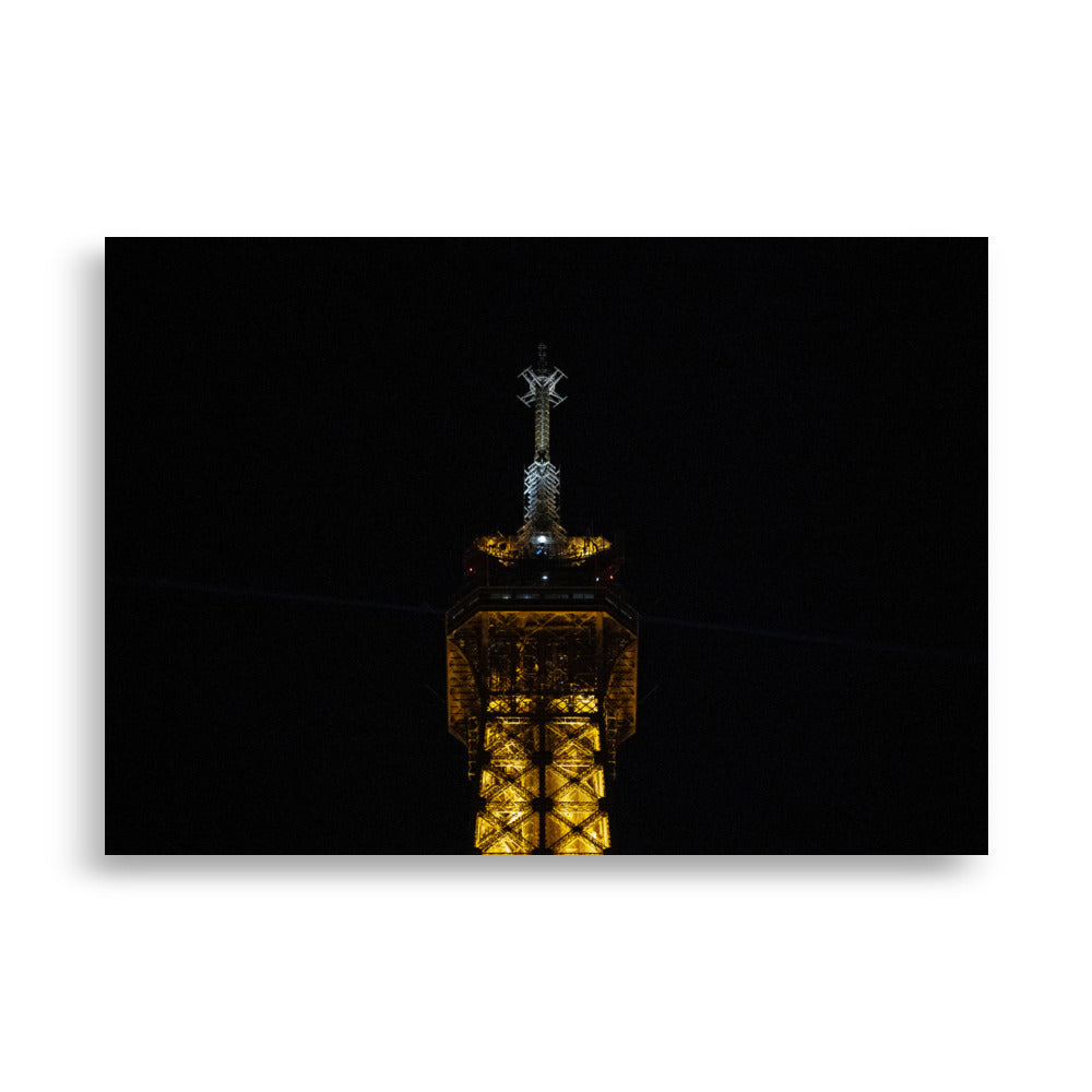 Photographie 'L'antenne' de la partie supérieure de la Tour Eiffel illuminée de nuit.