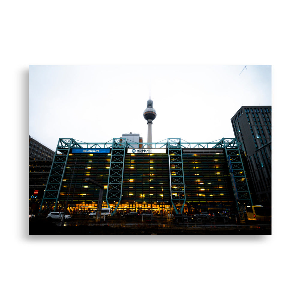 Photographie du parking moderne multi-étages "Parkhaus Rathauspassagen" à Berlin, illuminé avec la tour de télévision en arrière-plan.