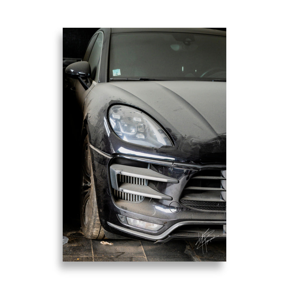 Photographie d'un Porsche Cayenne noir abandonné dans un garage poussiéreux.