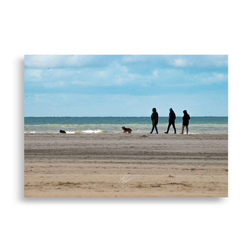 Photographie de la plage de Deauville avec des promeneurs et leur chien, capturant l'atmosphère tranquille et l'immensité de la mer normande.