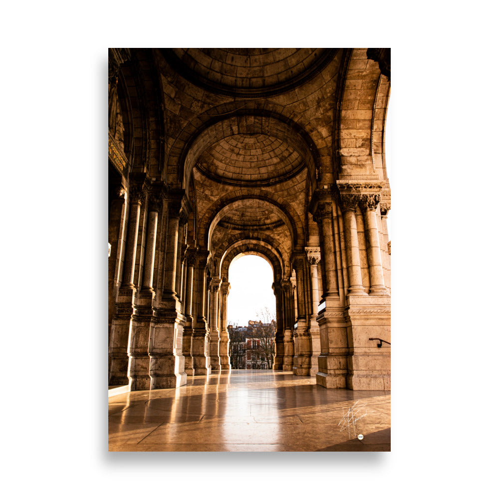 Photographie ensoleillée de la façade de l'entrée de la Basilique du Sacré Cœur à Montmartre, montrant l'architecture détaillée avec des reflets lumineux sur le sol pavé.