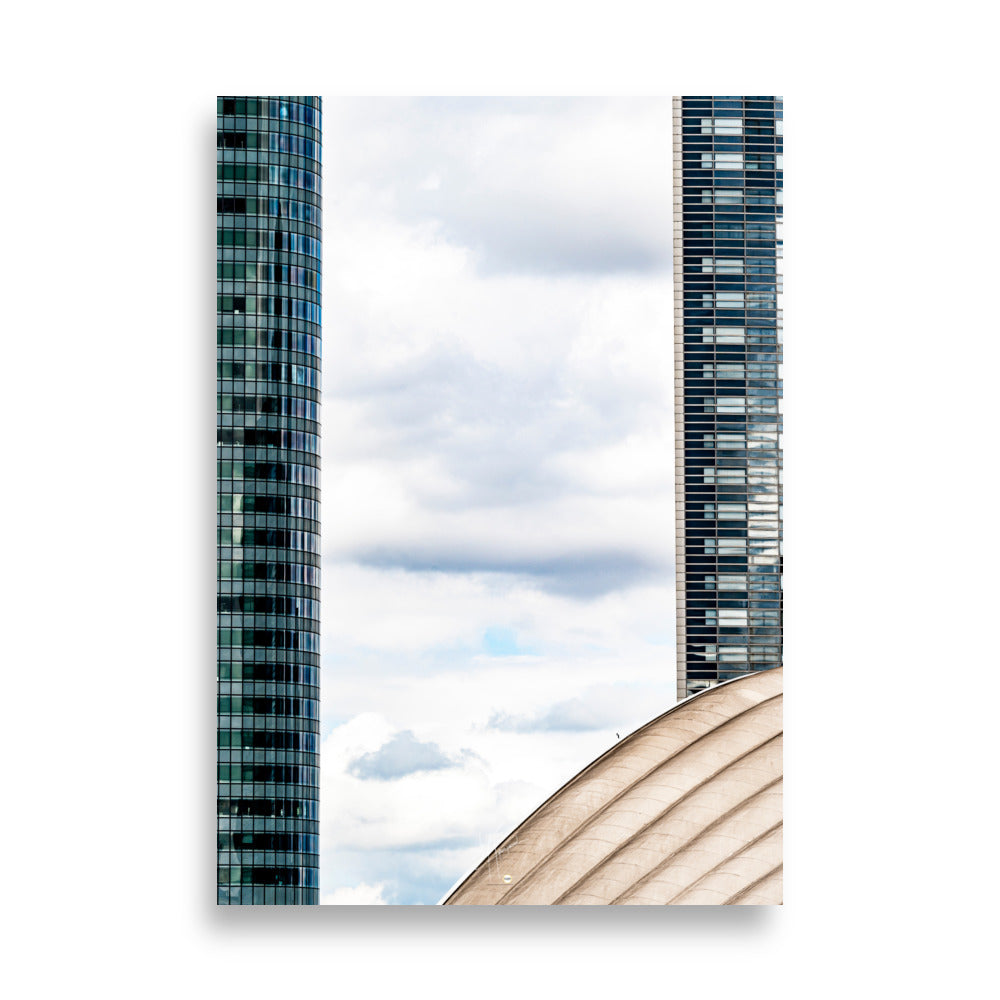 Fenêtre entre deux bâtiments en verre offrant une vue sur un ciel nuageux.