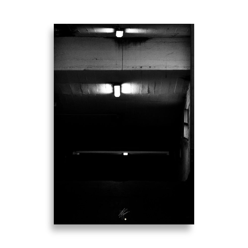 Photographie en noir et blanc intitulée 'Glaçant', montrant trois néons blancs éclairant une entrée de garage descendante dans une atmosphère sombre et mystérieuse.