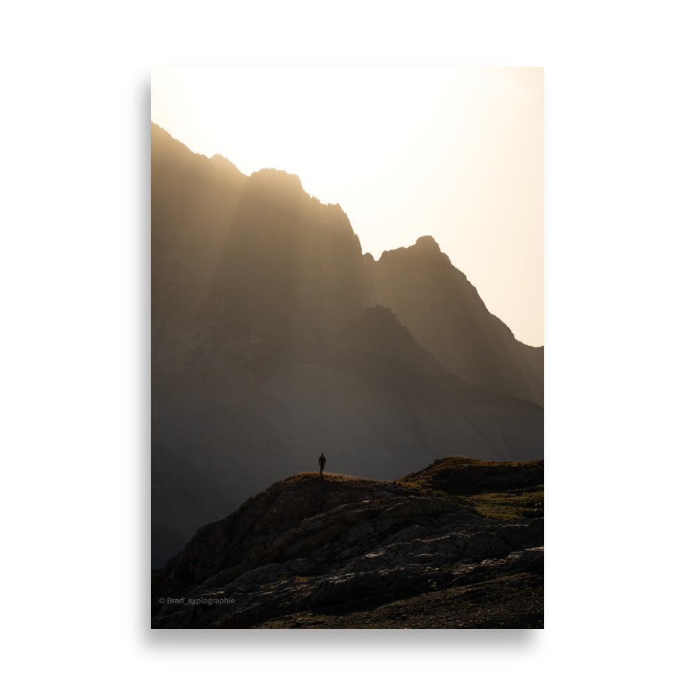 Vue panoramique des montagnes au coucher du soleil, où la lumière dorée enveloppe les pics et les vallées – une œuvre signée par Brad_explographie.