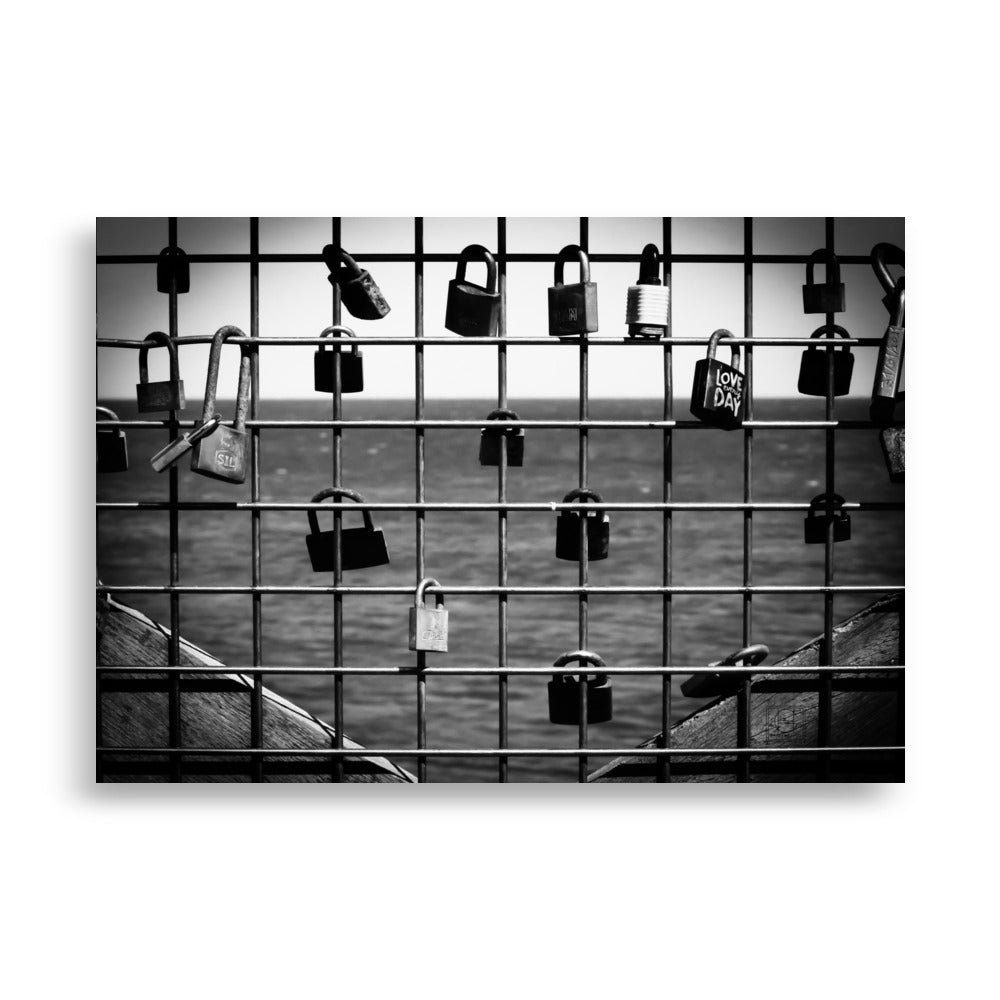 Poster 'L'accroche Cœurs' montrant des cadenas accrochés symbolisant des vœux d'amour avec la mer tranquille en arrière-plan, photographié par Hadrien Geraci. Un choix artistique idéal pour ajouter une touche romantique et d'espoir à votre intérieur.