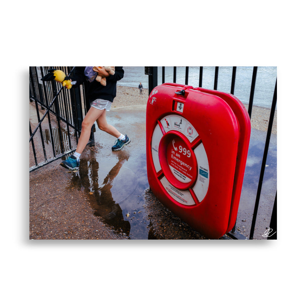 Photographie 'Il faut rentrer' par Ilan Shoham mettant en lumière une boite rouge d'urgence affichant le numéro 999, fixée sur une grille métallique, dans le contexte vibrant des rues de Londres.