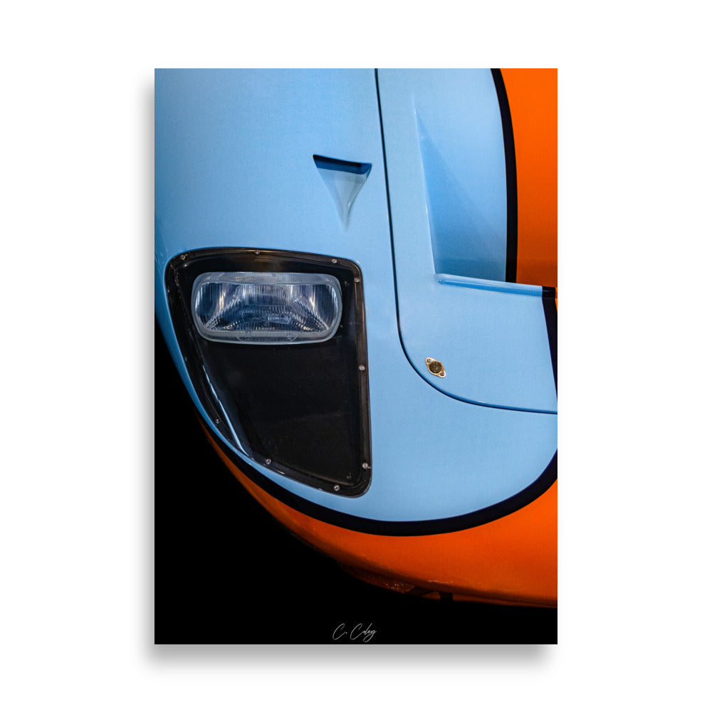 Poster 'GT40 Gulf' capturant la nostalgie de la Ford GT40 à travers un détail du bloc optique vintage et du capot bleu et orange, offrant une plongée visuelle dans l'histoire légendaire des courses automobiles par le photographe Charles Coley.