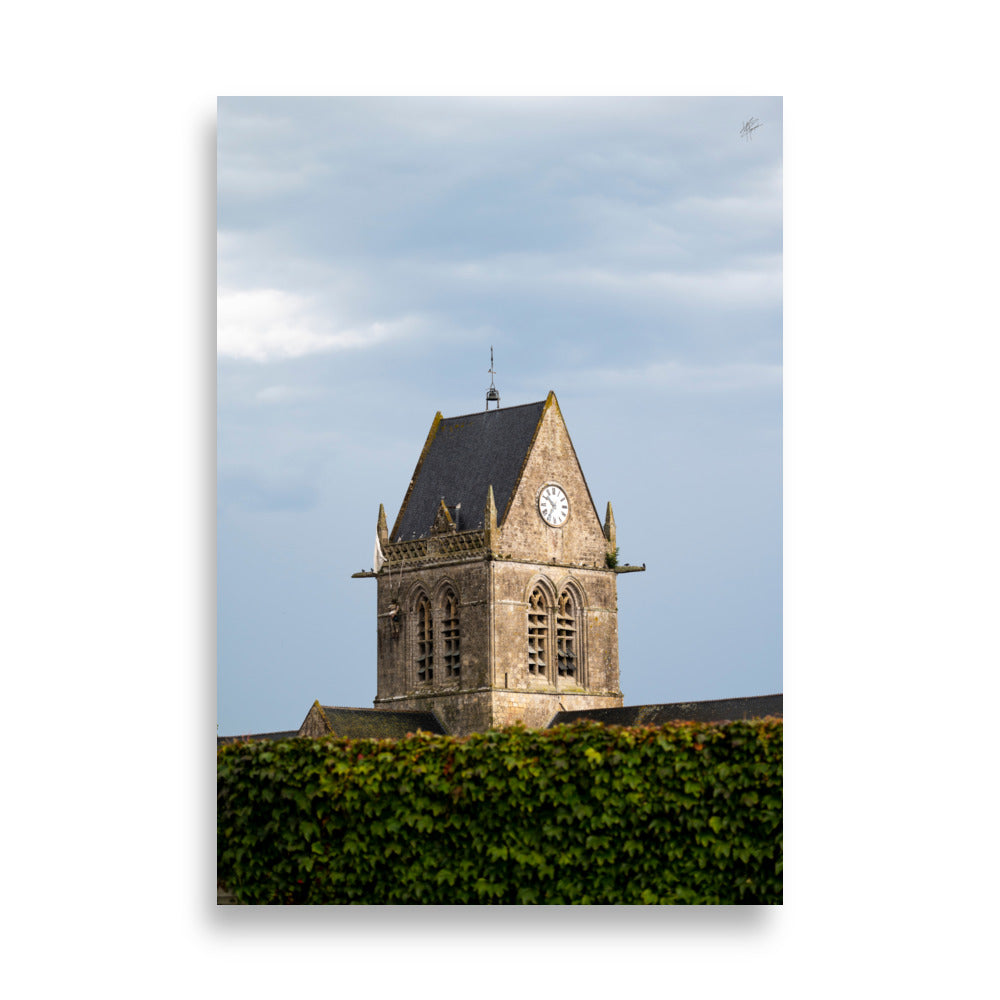 Vue pittoresque de l'église historique Sainte-Mère-Église sous un ciel nuageux, capturée dans un poster haut de gamme.