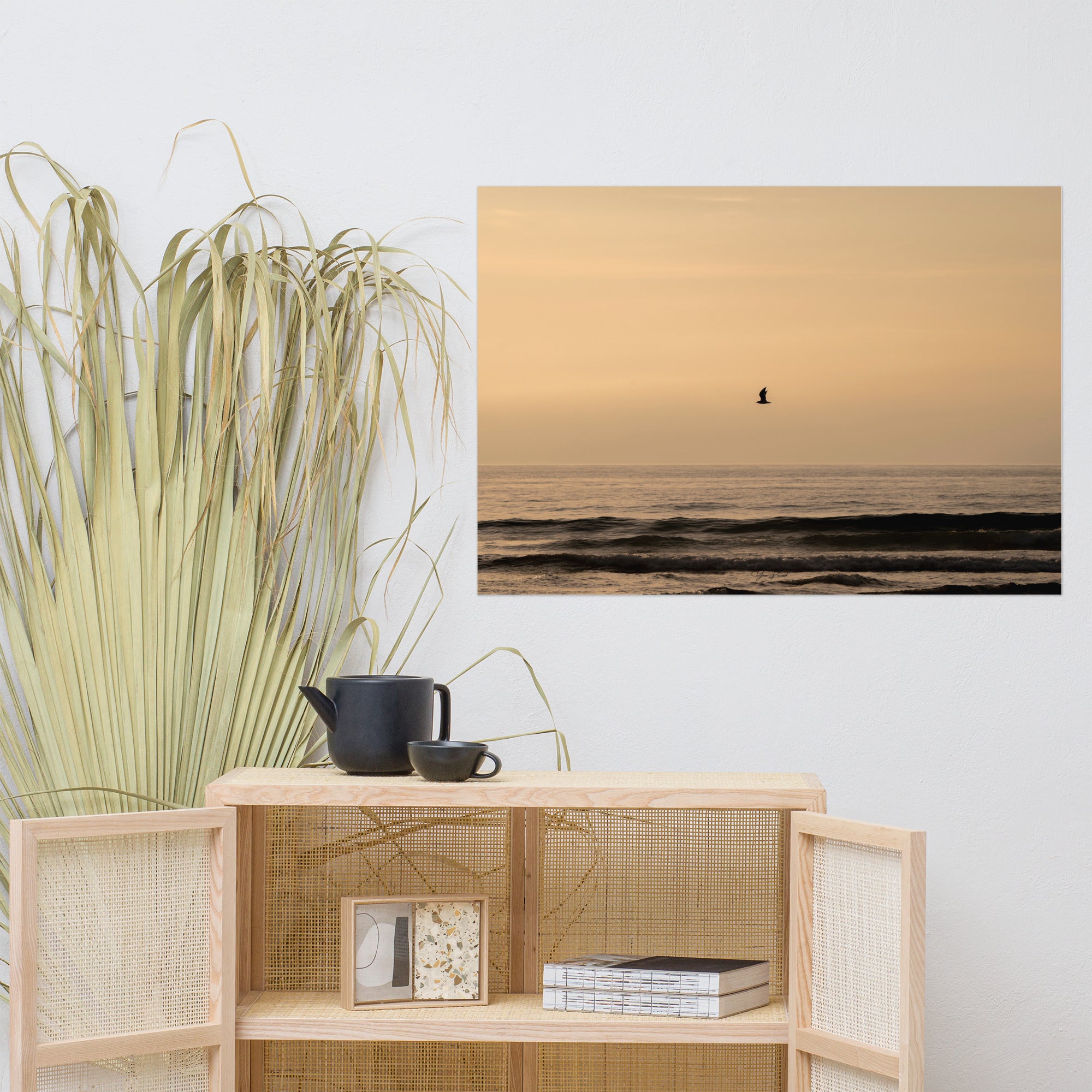 Photographie d'un coucher de soleil en bord de mer avec reflet du soleil sur les vagues, horizon doré et oiseau volant au-dessus de la mer.