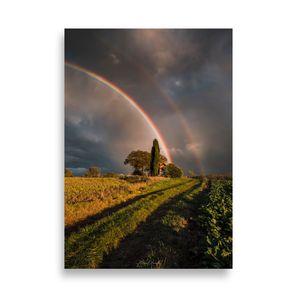 Photographie d'un paysage rural avec un double arc-en-ciel au-dessus d'une maison de campagne, capturée par Florian Vaucher, symbolisant un monde magique et plein d'espoir.