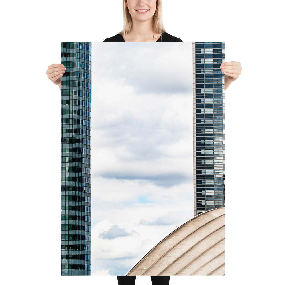 Fenêtre entre deux bâtiments en verre offrant une vue sur un ciel nuageux.