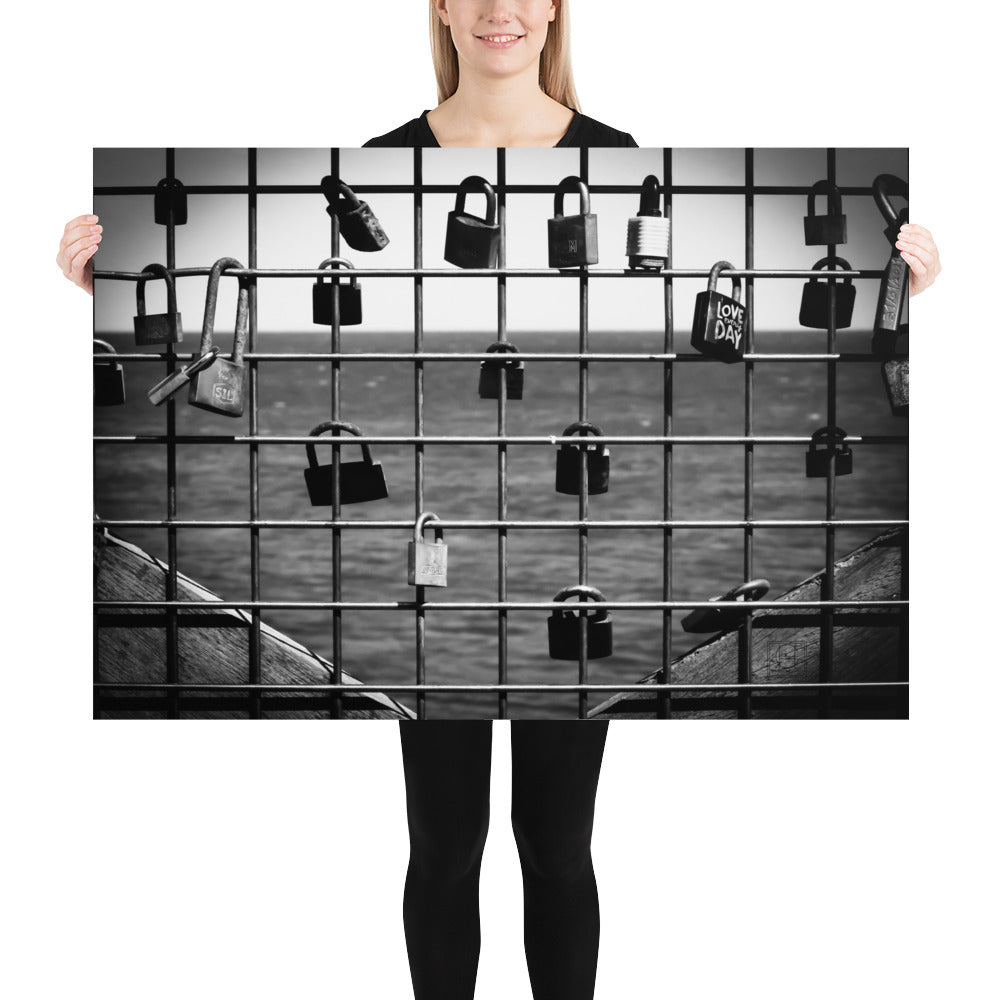 Poster 'L'accroche Cœurs' montrant des cadenas accrochés symbolisant des vœux d'amour avec la mer tranquille en arrière-plan, photographié par Hadrien Geraci. Un choix artistique idéal pour ajouter une touche romantique et d'espoir à votre intérieur.