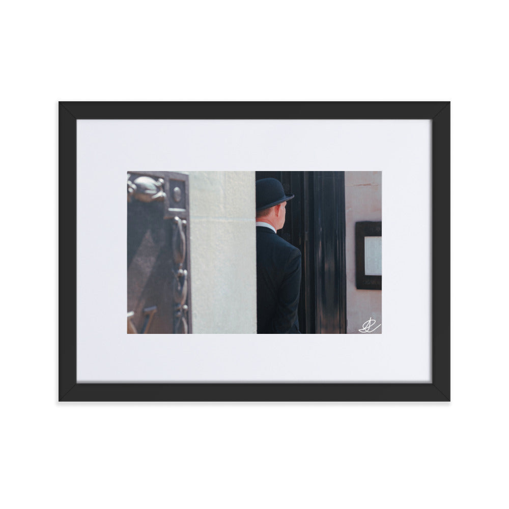 Photographie en noir et blanc 'Gardien d'Entrée' par Ilan Shoham, montrant un homme en costume noir vue de dos, patientant à l'entrée d'un édifice à Londres.