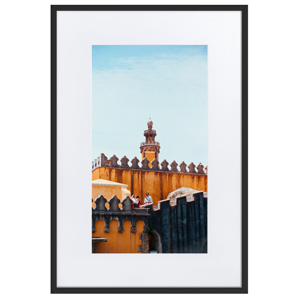 Photographie argentique 'Palais National de Pena' par Benjamin Peccard, représentant les murs orangés et patinés du palais historique sous la pluie, avec trois touristes semblant minuscules face à sa stature imposante, offrant une perspective élégante et historique pour la décoration murale.