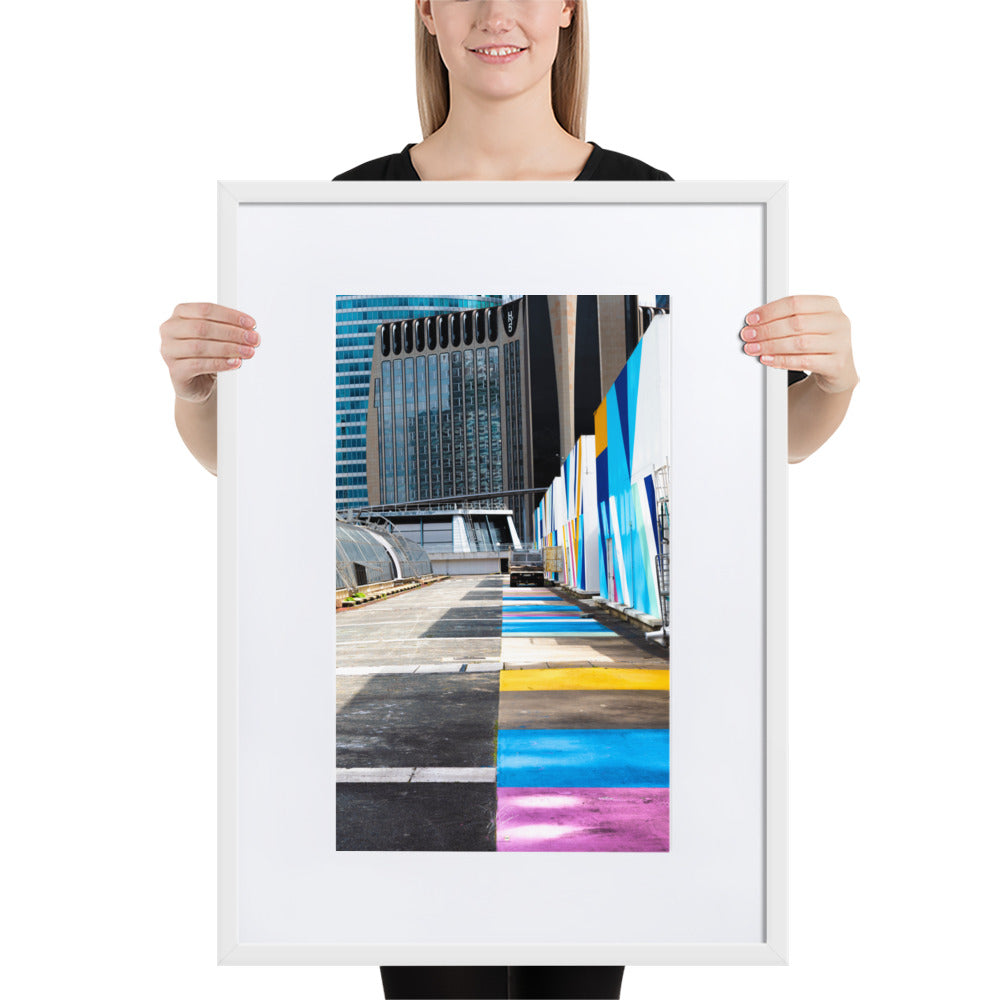 Poster encadré 'Palette' représentant une rue vibrante de couleurs contrastant avec des structures architecturales modernes, incarnant un mélange d'urbanisme et d'art.