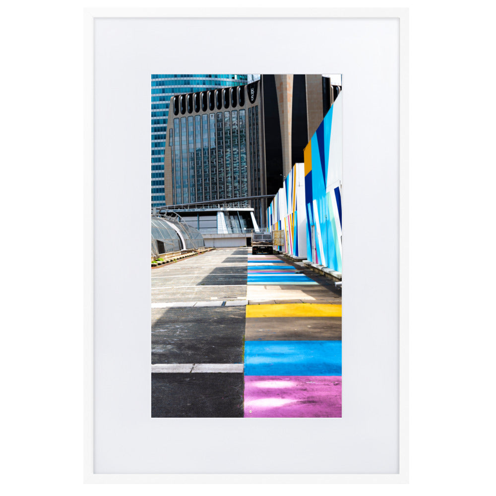 Poster encadré 'Palette' représentant une rue vibrante de couleurs contrastant avec des structures architecturales modernes, incarnant un mélange d'urbanisme et d'art.