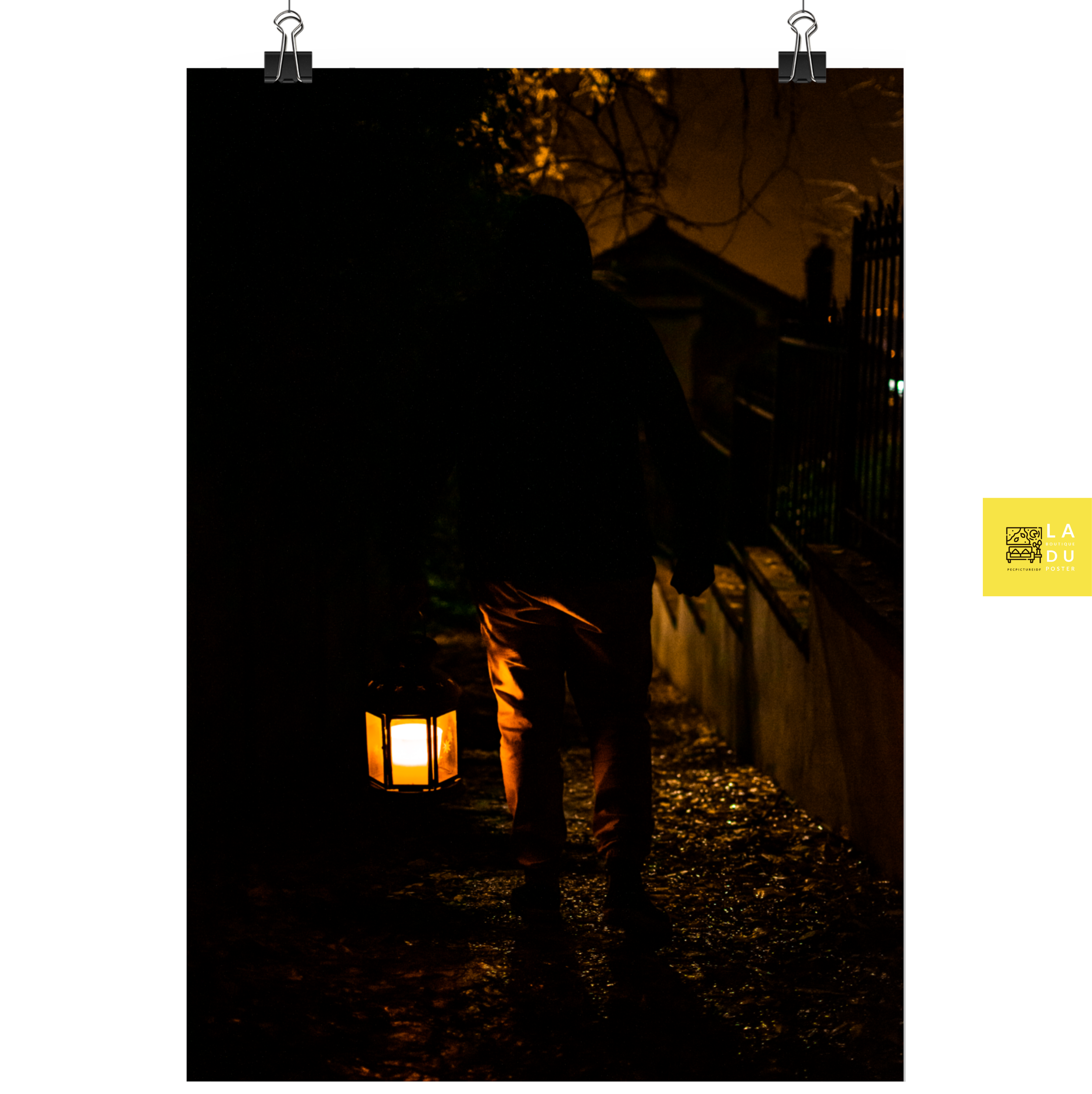 "La lanterne de Hagrid" - Poster de photographie : Un homme descend un chemin étroit en ville de nuit, éclairé par une lanterne, permettant une ambiance mystérieuse et captivante.